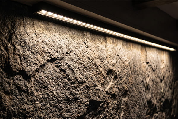 Light washing over a rough, matte stone wall surface